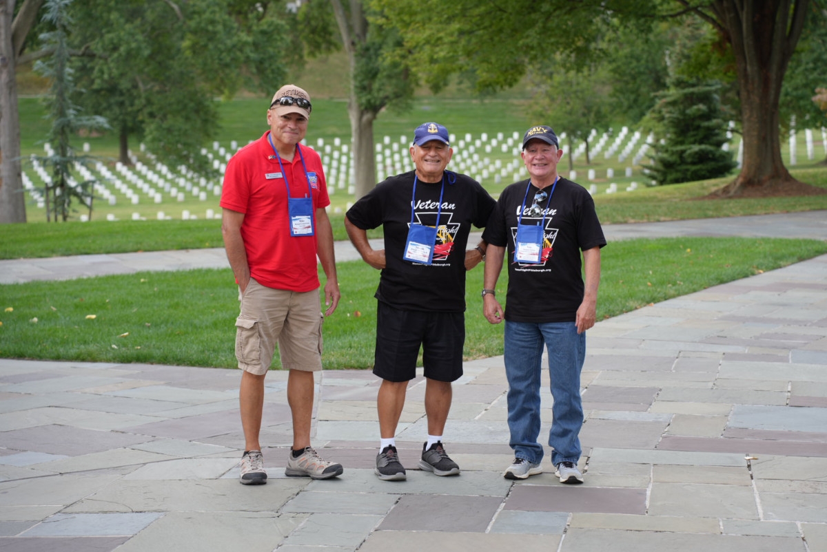 Two Veterans and an Honor Flight Guardian standing in front of Arlington National Cemetery