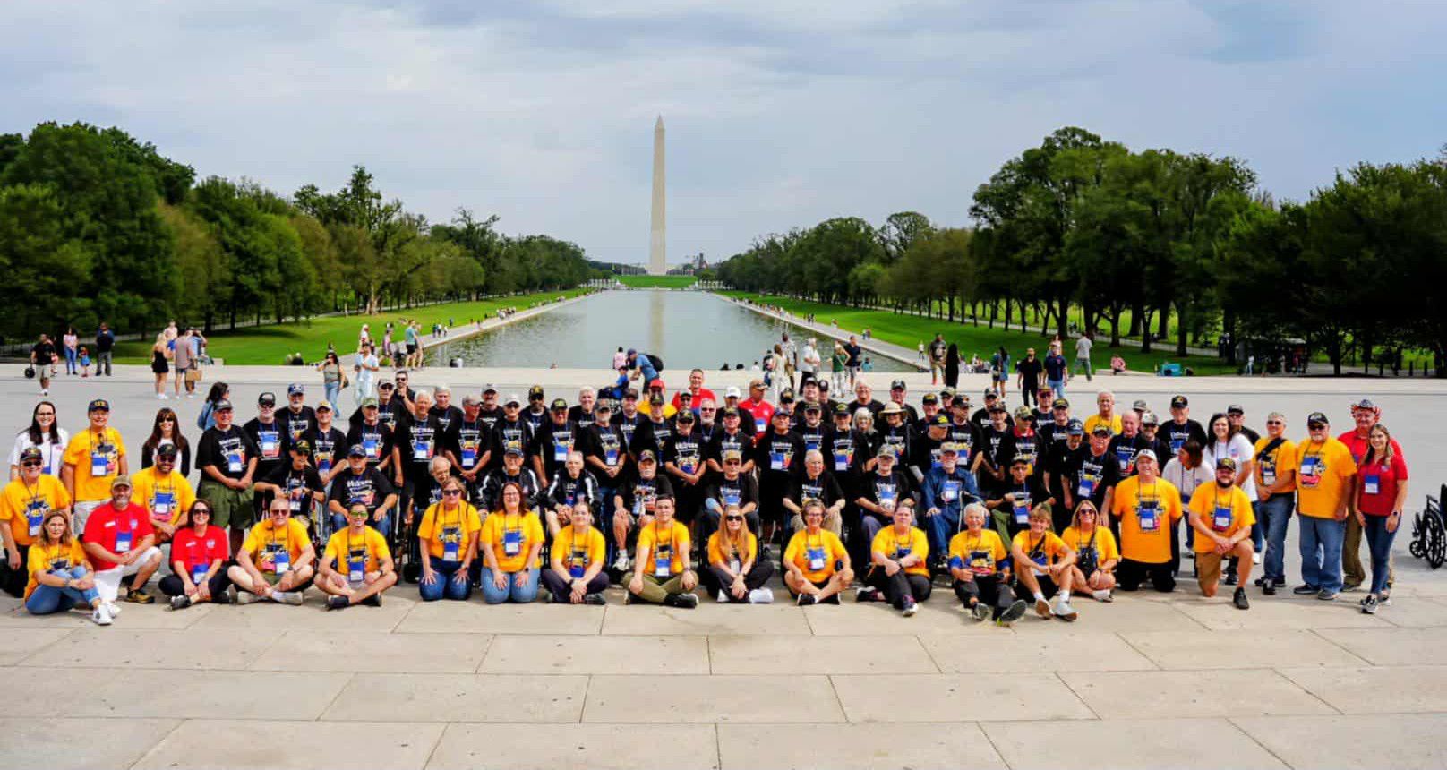 Group photo of Honor Flight Pittsburgh Mission 16 in front of the Lincoln Memorial Reflecting Pool and the Washinton Monument